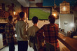 © Studio Romantic - A group of people watching tv football in a sports bar.