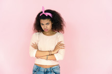 Sad Angry Serious Young African American Teenage Girl Mixed Race Woman Pout Lips Sulking Look At Camera. Stand Arms Crossed Feel Offended Face Isolated On Pink Studio Background