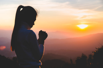 Wall Mural - Woman praying in the morning on the sunrise background. Christianity concept. Pray background. Faith hope love concept.
