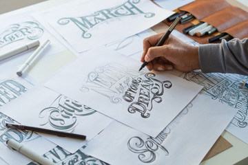 Typography Calligraphy artist designer drawing sketch writes letting spelled pen brush ink paper table artwork.Workplace design studio.