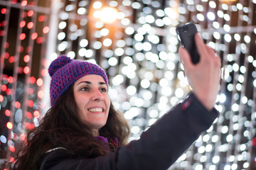 woman with smartphone land christmas lights sending message