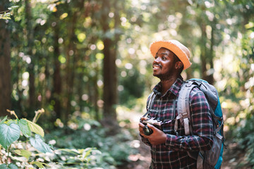 Wall Mural - African traveler man holding flim camera in the green forest