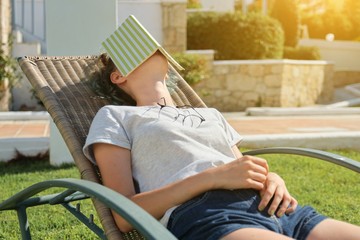 teen girl resting outdoor sitting in chair, reading book and sleeping