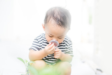 Wall Mural - Asian baby boy Looking At green leaf Through Magnifying Glass at home on white Background.Concept for research global warming, global network,SEO search engine and Kid Education of ecology.