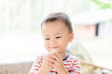 Wall Mural - Happy Little asian baby boy eating jam roll at home in summer.Concept for dessert in meal and happy hungry face in food.