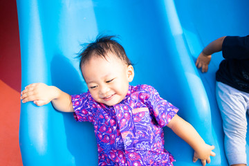 Wall Mural - 2 years old asian boy play slide in playground.Enjoying time in the park.