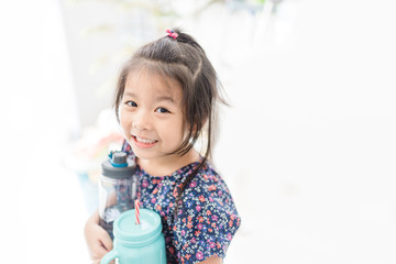 Wall Mural - Little asian girl holding reuse bottle for drink.Reusable products, plastic free, eco living and Zero waste concept.Ecology go green,Save the earth concept.