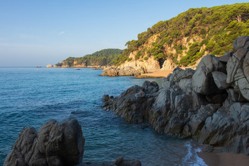 Fototapete - Spain beach in Lloret de Mar. Cala de Boadella platja. Rocks on sandy beach in Europe, Costa Brava. Scenic landscape of Mediterranean sea bay
