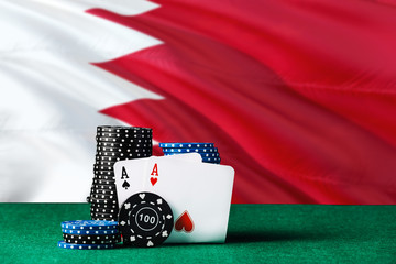 Bahrain casino theme. Two ace in poker game, cards and black chips on green table with national flag background. Gambling and betting.