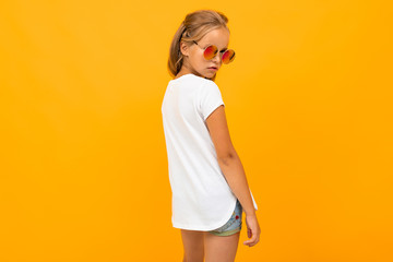 bright girl in sunglasses in a white t-shirt with a mockup stands back on a yellow background