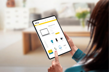 Poster - Shopping online from home concept. Woman holding tablet and search for laptops online. Modern, flat design online store web site
