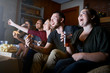 © Joshua Resnick - friends watching tv together eating pizza and potato chips