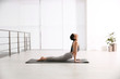 © New Africa - Young woman practicing cobra asana in yoga studio. Bhujangasana pose