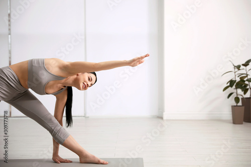 Fotomural Young woman practicing triangle asana in yoga studio