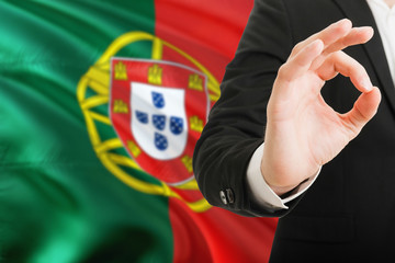 Wall Mural - Portugal acceptance concept. Elegant businessman is showing ok sign with hand on national flag background.