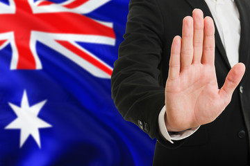 Wall Mural - Australia rejection concept. Elegant businessman is showing stop sign with hand on national flag background.