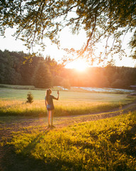 Girl taking photo on phone in nature during sunset