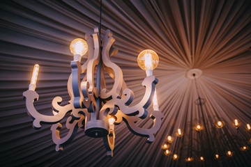 Two antique wooden chandeliers on an tent ceiling in a restoraunt.