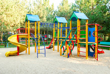Colorful Playground On Yard In The Park. Colorful Children Playground,exercise Kid,activities In Outdoor Public Park Surrounded By Green Trees