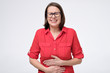 Pretty woman in glasses and red shirt with stomach pain on white background