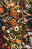 Fototapeta Uliczki - Traditional Turkish celebration dinner at rustic table. Flat-lay of people eating Turkish salads, cooked vegetables, meze starters, pastries and drinking raki drink, top view. Middle Eastern cuisine
