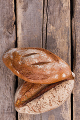 Fresh bread on cracked wooden boards. Whole wheat bread on rustic wooden background, top view.