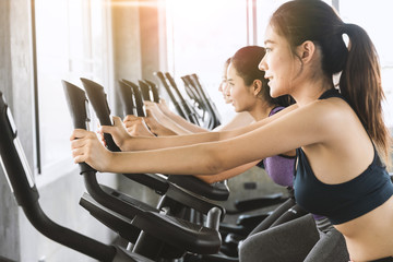 Group of smile women work out together on exercise bike at the indoor gym. Healthy lifestyle sport concept.