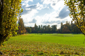 A playing field in autumn with a distant soccer match. Photo taken at Chinbrook Meadow, at Grove Park in Lewisham, London