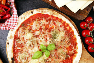 Pizza with tomatoes, mozzarella cheese, basil. Delicious italian pizza on wooden pizza board.