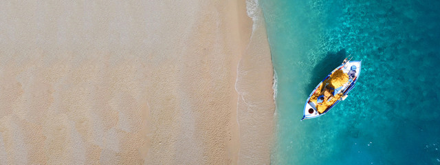 Aerial drone top down ultra wide photo of traditional fishing boat docked in Ionian deep turquoise sea, Greece