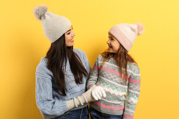 Sticker - Happy mother and daughter in warm clothes on yellow background. Winter vacation