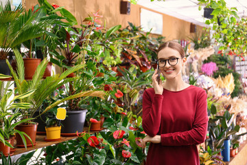 Wall Mural - Female business owner talking on mobile phone in flower shop