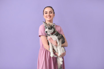 Wall Mural - Cute woman with funny husky puppy on color background