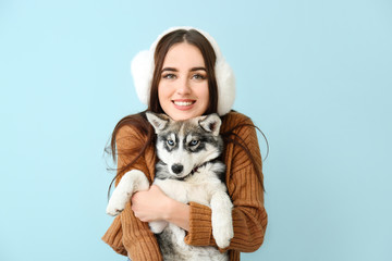 Cute woman with funny husky puppy on color background