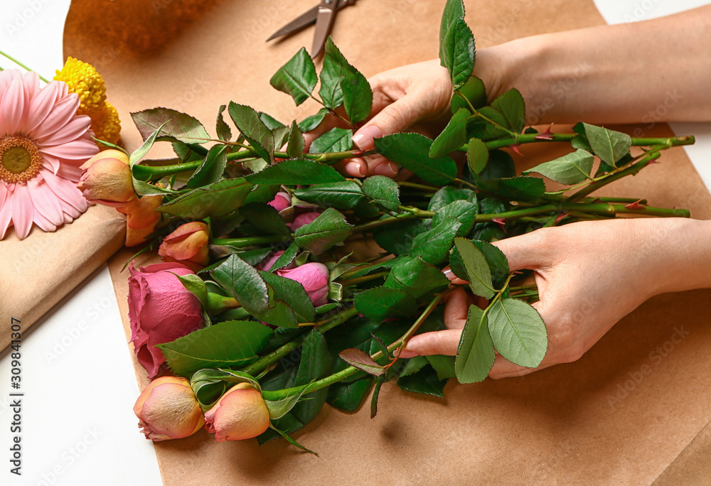 Female florist making beautiful bouquet on white background