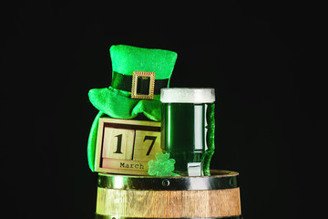 Mug of green beer, Leprechaun's hat, calendar and barrel on dark background. St. Patrick's Day celebration