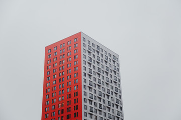 one residential multi-storey building - a tower of red-white color against a gray sky 1