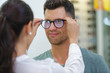 handsome man choosing glasses in optics store