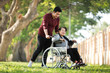 © chayathon2000 - Asian senior woman sitting on the wheelchair with her son  happy smile face on the green park