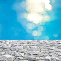 Gray stone top and blurry blue water bokeh background