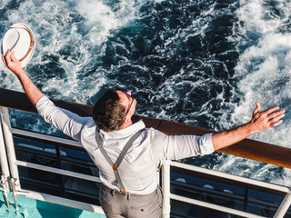 Smiling man on the empty deck of a cruise liner on the background of sea waves. Top view, close-up. Concept of leisure and travel