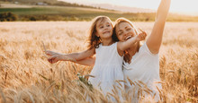 Portrait Of A Happy Young Mother And Her Lovely Daughter Playing And Laughing In A Field Of Wheat . Freedom Concept.