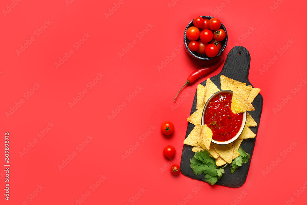 Board with tasty nachos and sauce on color background