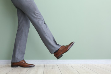 Young man in stylish shoes near color wall