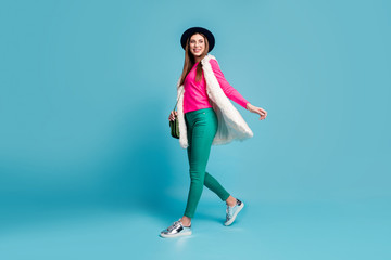 Sticker - Full length photo of pretty modern stylish look lady walking down street tourist traveler good mood wear vintage hat trousers fur vest pink jumper isolated blue background