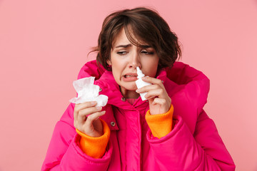 Poster - Portrait of unhappy young woman holding napkin and using nasal spray