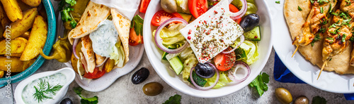 Fotomural Greek food: greek salad, chicken souvlaki, gyros and baked potato wedges on gray background, top view