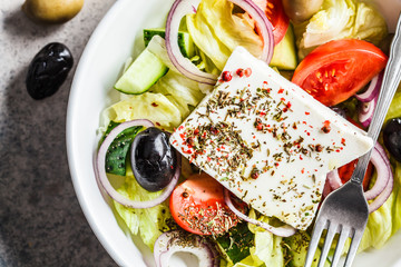 Wall Mural - Traditional greek salad with feta, olives, tomato and cucumber in a white dish, top view.