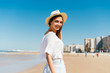 © mnelen.com - girl in a hat joyfully looked over her shoulder against the backdrop of sand, water and buildings