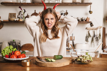 Wall Mural - Image of angry cute woman making horns with bell peppers